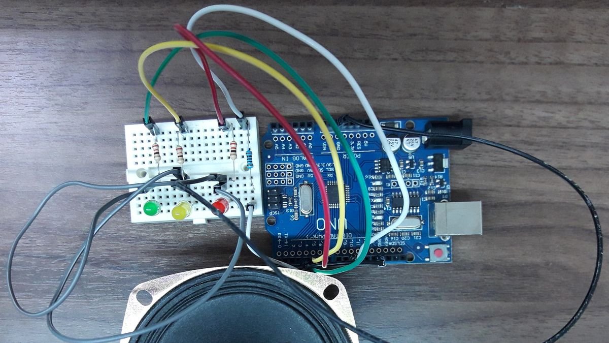 Carte Arduino UNO câblée à une petite breadboard avec trois LED, des résistances et un haut-parleur