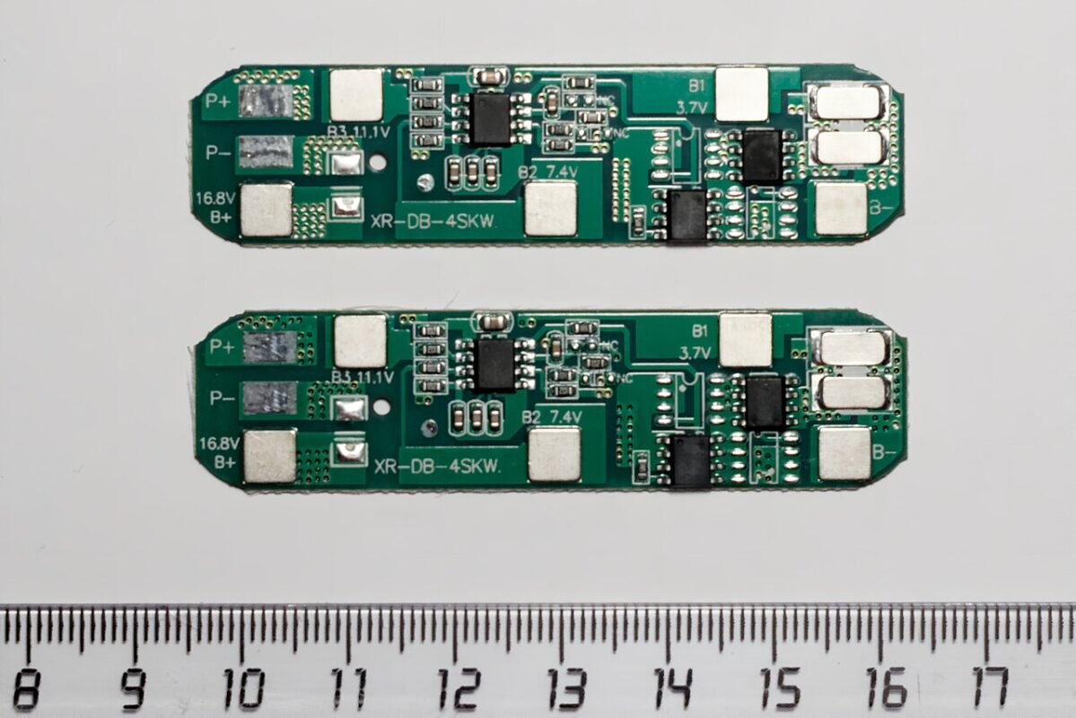 Deux cartes de protection BMS 4S pour batterie lithium posées au-dessus d’une règle graduée