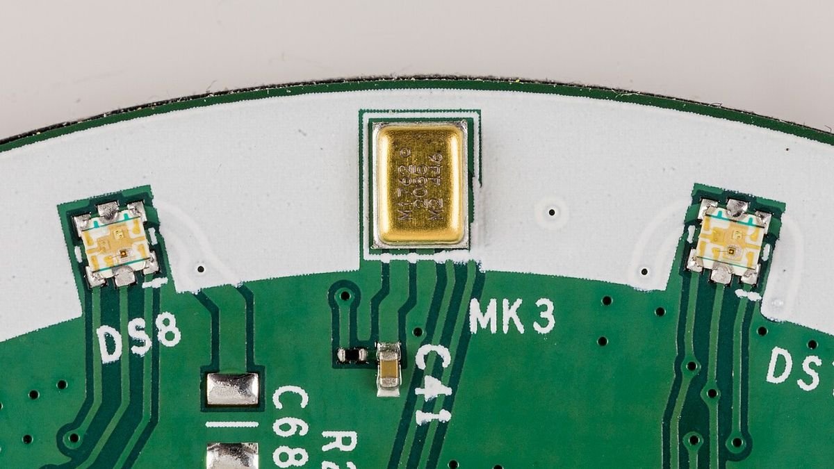 Gros plan d’un microphone MEMS soudé sur le circuit imprimé d’une enceinte connectée, entre deux LED