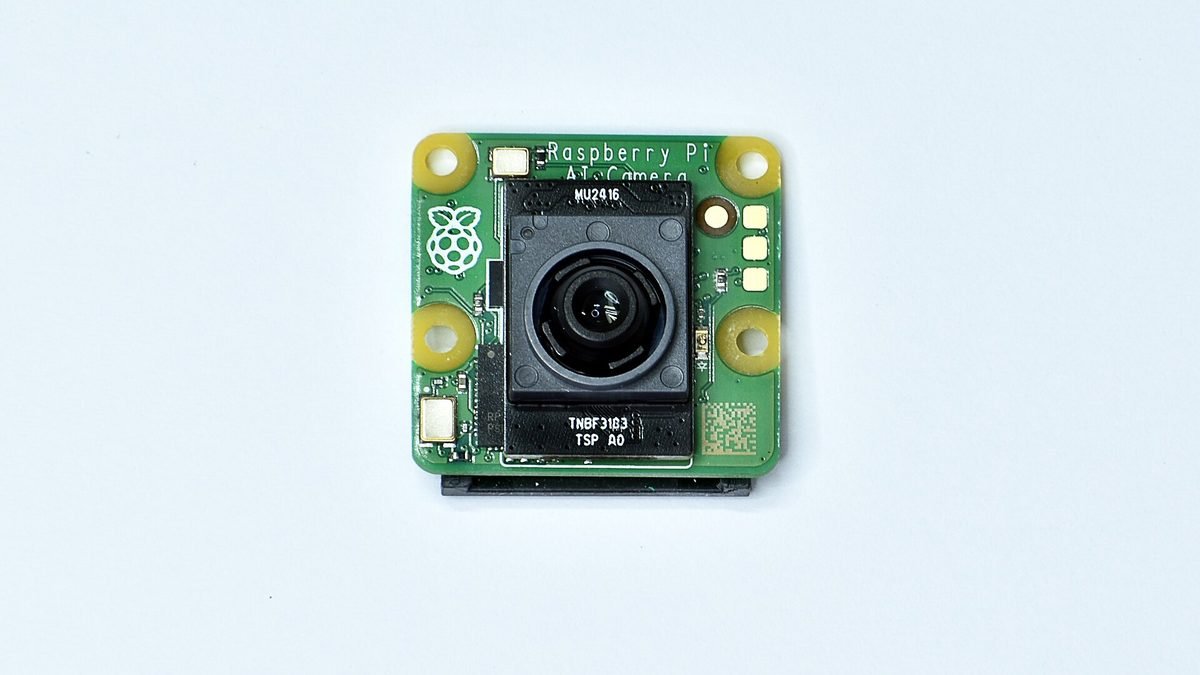 Module Raspberry Pi AI Camera vu de face, avec objectif au centre et logo Raspberry Pi
